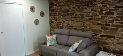 a couch in a room with a brick wall at Apartamentos Fons sacrata in Fonsagrada