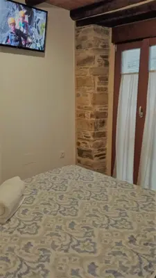 a bedroom with a bed and a tv on the wall at Apartamentos Fons sacrata in Fonsagrada