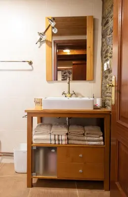 a bathroom with a sink and a shelf with towels at As Veneiras Casa in Neipín
