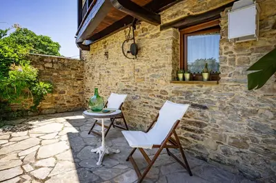 a patio with two chairs and a table and a window at Casa Peleyón in Castropol