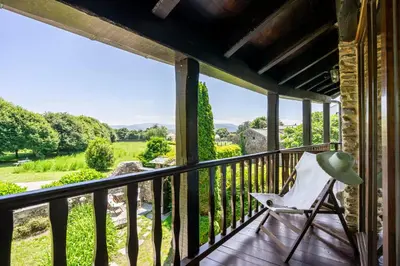 a rocking chair on the porch of a house with a view at Casa Peleyón in Castropol