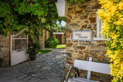 a sign on the side of a building with a bench at Casa Peleyón in Castropol