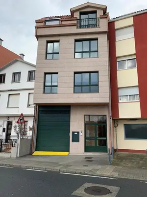 a building with a green garage door on a street at Luky Miño in Miño