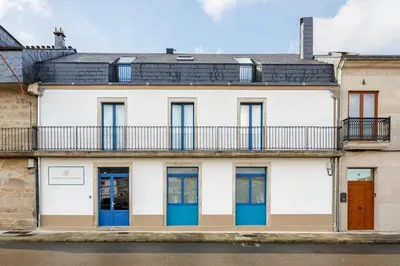 an apartment building with blue doors and a balcony at Hotel Casa da Galbana in Friol