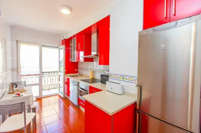 a red kitchen with a refrigerator and a table at APARTAMENTO RIAMAR - A ESTRENAR in Ribadeo