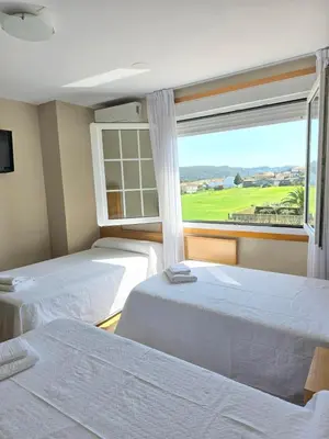 a room with three beds and a window at Pensión Pedrouzo in O Pedrouzo