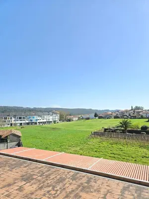 a view of a green field with buildings in the background at Pensión Pedrouzo in O Pedrouzo