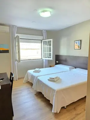 a bedroom with two beds and a window at Pensión Pedrouzo in O Pedrouzo