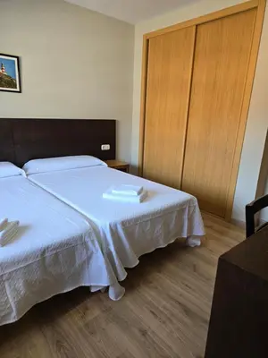 a bedroom with two beds with white sheets and wooden floors at Pensión Pedrouzo in O Pedrouzo