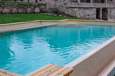 a large swimming pool with a wooden bench in it at Hotel La Rectoral in Covelo