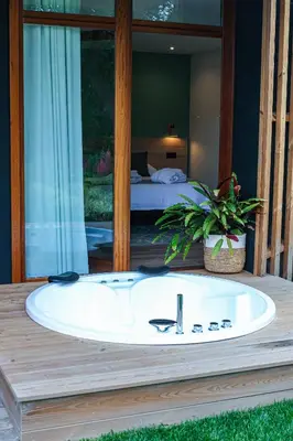 a white bath tub on a deck with a bedroom at Hotel La Rectoral in Covelo