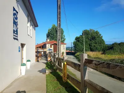 a wooden fence next to a building and a sidewalk at Albergue El Aleman in Boente