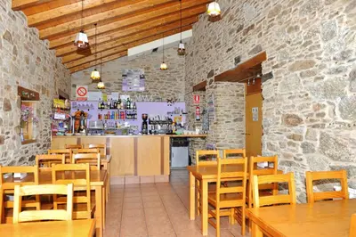 a restaurant with wooden tables and chairs and a counter at Albergue El Aleman in Boente