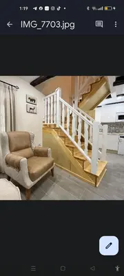 a living room with a chair and a staircase at APARTAMENTOS TURISTICOS LAS CANDELAS in Puebla de Sanabria