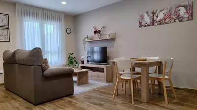 a living room with a couch and a table and a television at APARTAMENTOS TURISTICOS LAS CANDELAS in Puebla de Sanabria