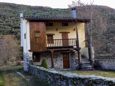 an old house with a balcony on a stone wall at Casa Rural El Llao Y Los Fresnos in Murias de Paredes