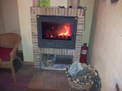 a brick fireplace with a fire in it at Casa Rural El Llao Y Los Fresnos in Murias de Paredes