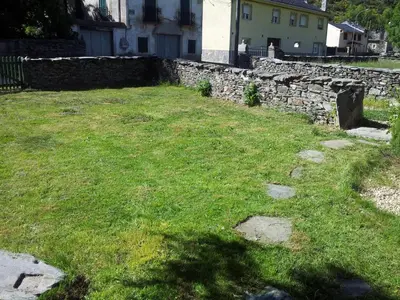 a yard with a stone wall and green grass at Casa Rural El Llao Y Los Fresnos in Murias de Paredes