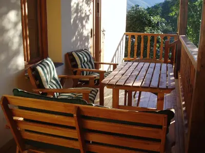 a porch with three chairs and a wooden table and bench at Casa Rural El Llao Y Los Fresnos in Murias de Paredes
