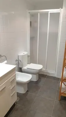 a white bathroom with a toilet and a shower at Alborada in Viveiro