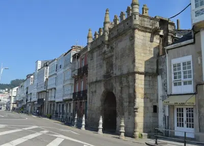 an old stone building with an archway on a street at Alborada in Viveiro