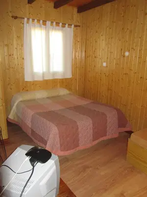 a bedroom with a bed and a window and acomputer at Cabañas Maleixas in El Puente