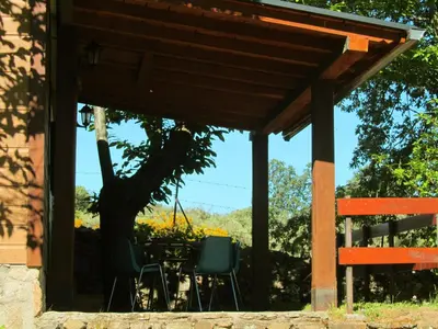 a patio with a table and chairs under a roof at Cabañas Maleixas in El Puente