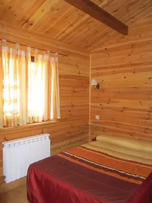 a bedroom with a bed in a log cabin at Cabañas Maleixas in El Puente