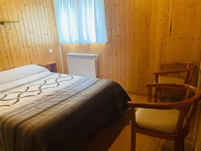 a bedroom with two chairs and a bed and a window at Cabañas Maleixas in El Puente