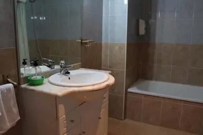 a bathroom with a sink and a bath tub at Apartamentos Los Gemelos in Foz