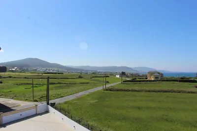 a view of a grassy field with a road at Apartamentos Los Gemelos in Foz