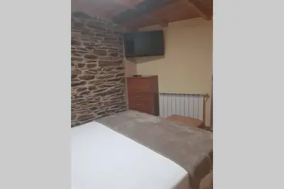 a bedroom with a bed and a brick wall at Apartamento con vistas al río A Solaina in Samos