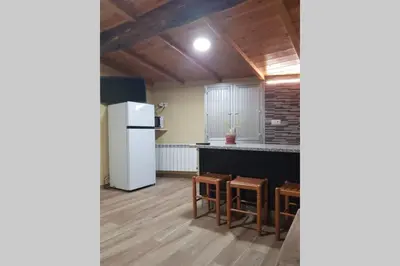 a kitchen with a refrigerator and some tables and chairs at Apartamento con vistas al río A Solaina in Samos