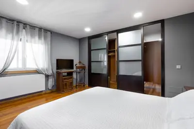 a bedroom with a white bed and a television at LE LLAR casa con 2 PISCINAS 1 CLIMATIZADA INTERIOR muy cerca de Santiago de Compostela in Amés