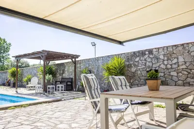 a patio with a table and chairs next to a stone wall at LE LLAR casa con 2 PISCINAS 1 CLIMATIZADA INTERIOR muy cerca de Santiago de Compostela in Amés