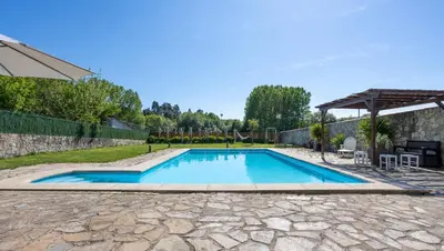 a swimming pool in a yard with a stone patio at LE LLAR casa con 2 PISCINAS 1 CLIMATIZADA INTERIOR muy cerca de Santiago de Compostela in Amés