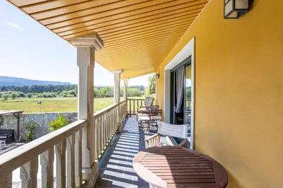 a balcony with a table and chairs on it at LE LLAR casa con 2 PISCINAS 1 CLIMATIZADA INTERIOR muy cerca de Santiago de Compostela in Amés