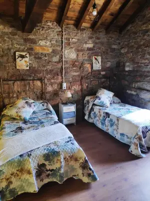 a bedroom with two beds and a stone wall at Apartamentos C'Ambrosio in La Peral