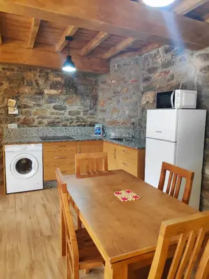 a kitchen with a wooden table and a white refrigerator at Apartamentos C'Ambrosio in La Peral