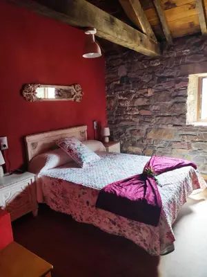 a bedroom with a bed and a stone wall at Apartamentos C'Ambrosio in La Peral