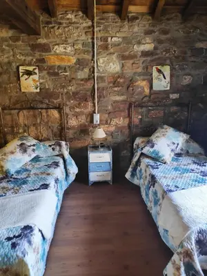 two beds in a room with a stone wall at Apartamentos C'Ambrosio in La Peral
