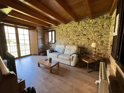a living room with a couch and a stone wall at Casa rural LA TORRE recién rehabilitada. in Las Herrerías