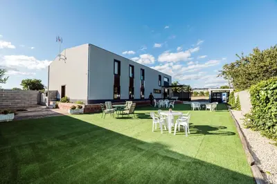 a patio with chairs and tables on a lawn at Albergue Santiago 15 Monforte in Monforte de Lemos