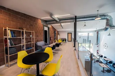 a classroom with yellow chairs and tables and a brick wall at Albergue Santiago 15 Monforte in Monforte de Lemos