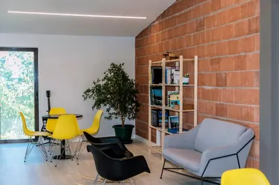 a room with chairs and a table and a brick wall at Albergue Santiago 15 Monforte in Monforte de Lemos