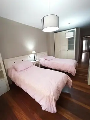 two beds in a bedroom with pink sheets at Viveiro Histórico in Viveiro