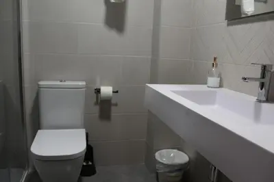 a bathroom with a white toilet and a sink at Hotel Rego Foz in Foz