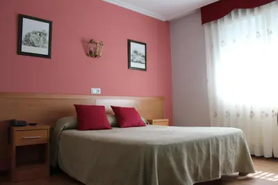 a bedroom with pink walls and a bed with red pillows at Hotel Rego Foz in Foz