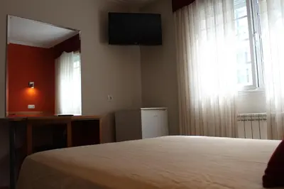 a bedroom with a bed and a television and a window at Hotel Rego Foz in Foz
