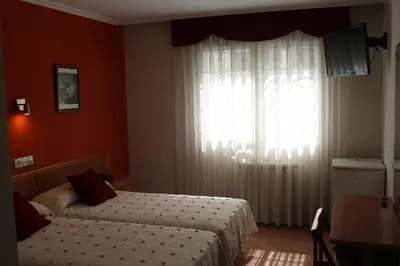 a bedroom with two beds and a large window at Hotel Rego Foz in Foz